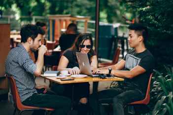 two men and one women sitting at a table socializing